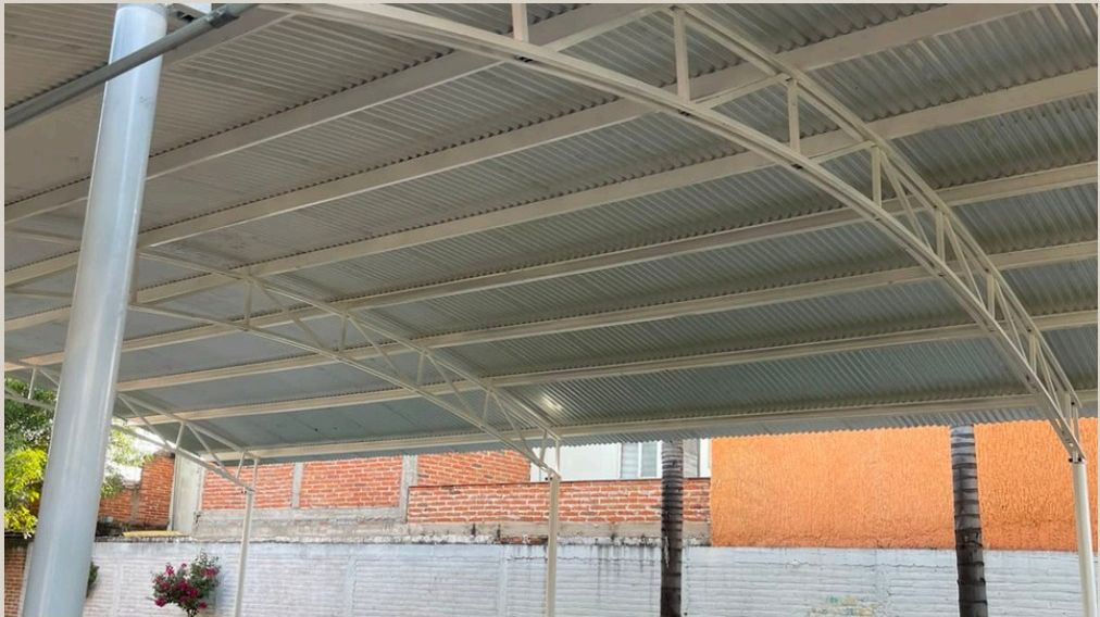Patio y edificio escolar bajo la techumbre metálica